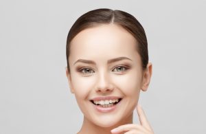 Smiling young woman with an oval face shape and smooth skin.